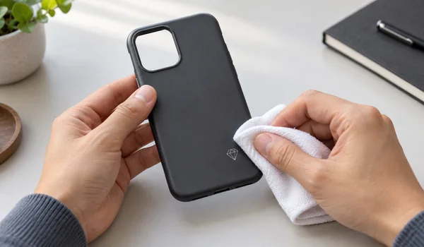Hands reviewing a small printed geometric mark on a phone case with a white cloth.